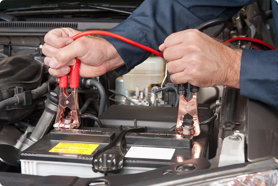 car mechanic uses battery jumper cables charge dead battery