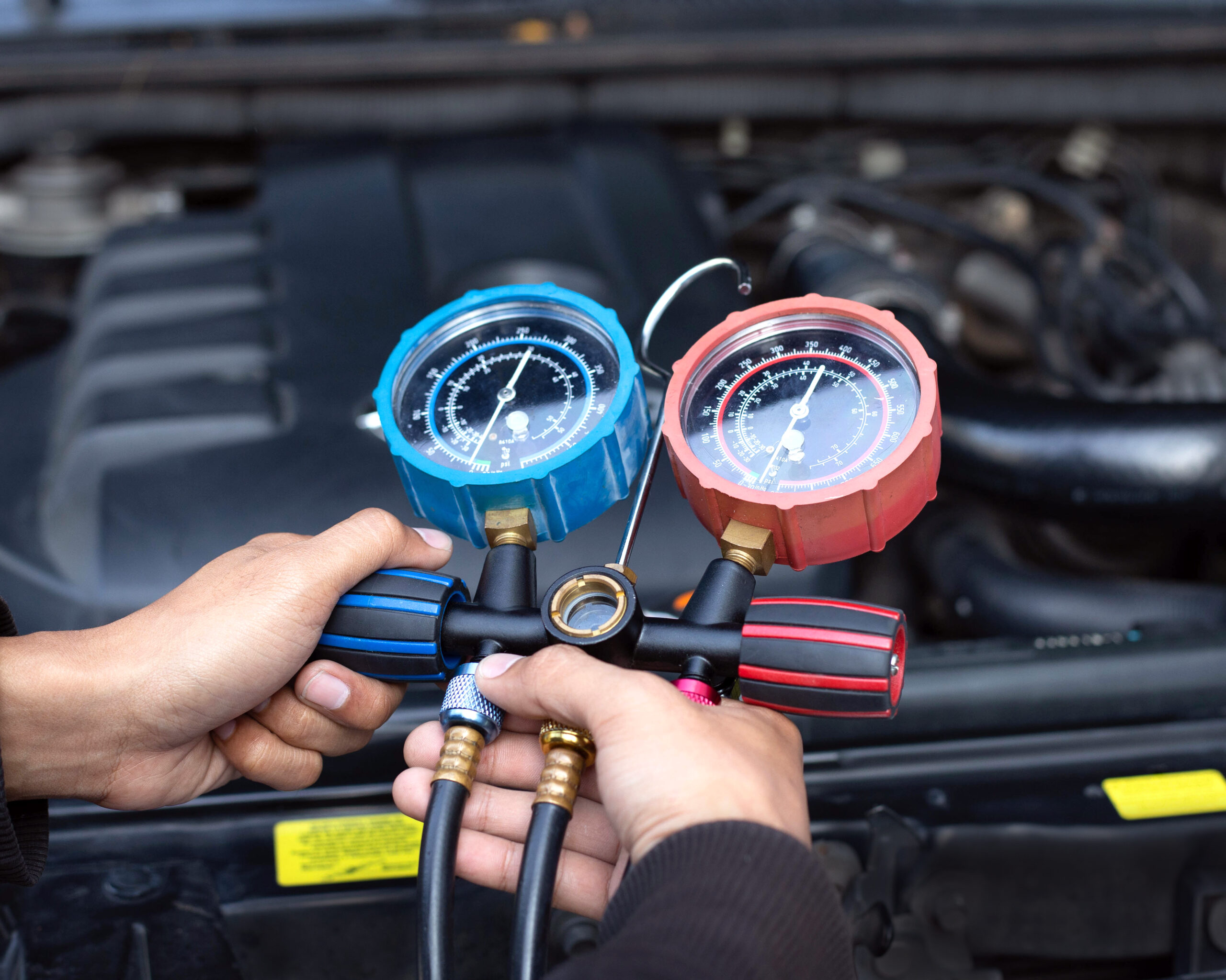 Vehicle air conditioning system being serviced with refrigerant pressure gauges during AC repair and maintenance