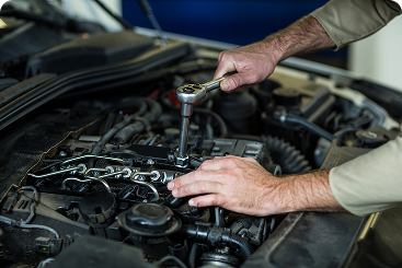 Auto technician repairing a vehicle engine with tools during professional engine repair and maintenance service